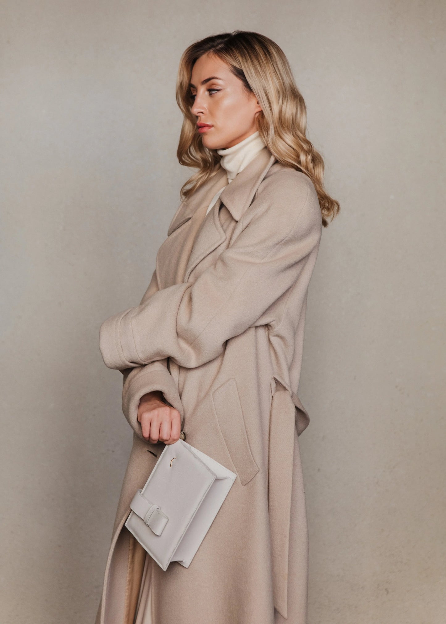 Model with coat and Qosmic Elara Moonstone - cream handbag -
